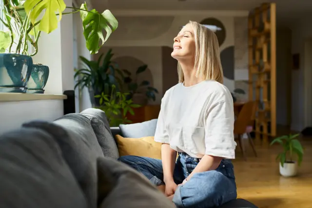 mujer feliz meditando en su salon